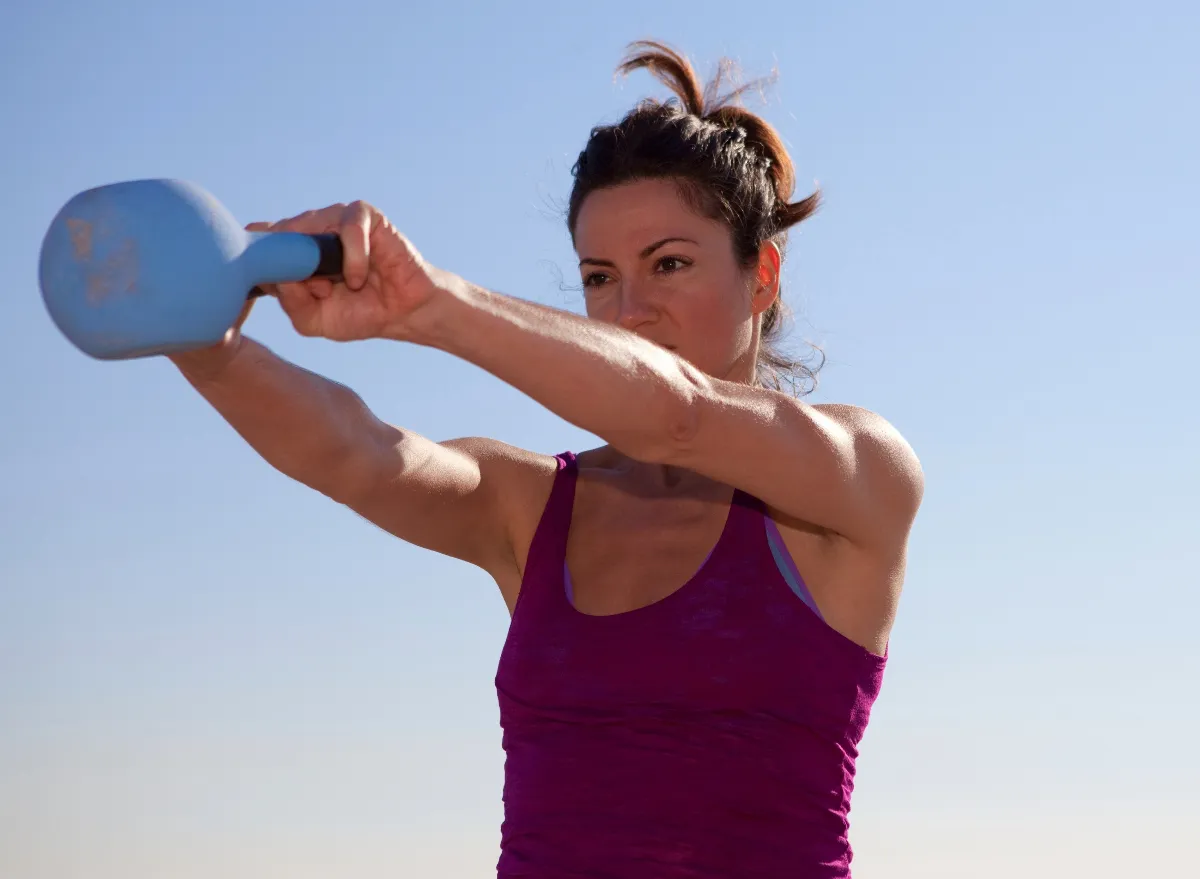 woman doing kettlebell swings, concept of strength exercises for women to melt middle-aged spread belly fat