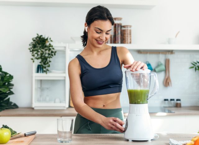woman making green smoothie, concept of habits to slim down a thick waist in 30 days