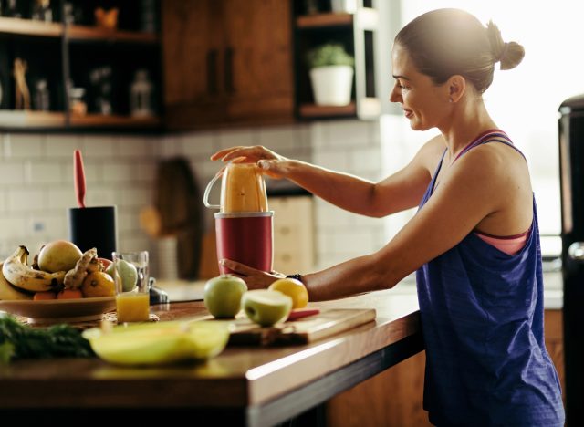 γυναίκα που φτιάχνει smoothie φρούτων, έννοια των συνηθειών που ανατινάζουν το λίπος της κοιλιάς