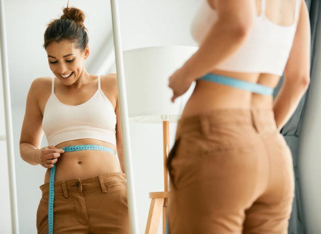 woman measuring belly in mirror, concept of easiest ways for women to lose belly fat