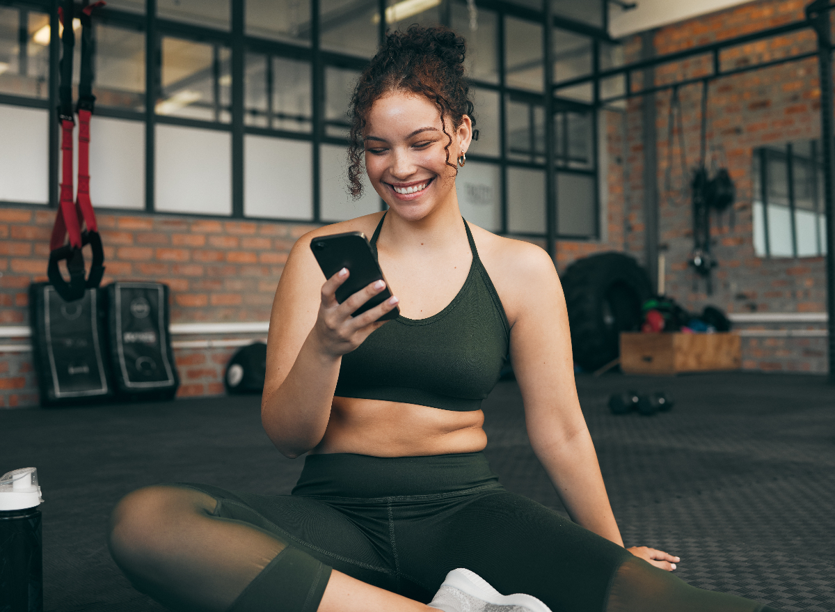 fitness woman on her phone at the gym concept of best Instagram trainers to follow