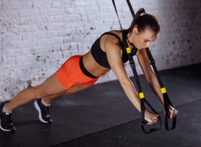 woman doing TRX pushups, concept of strength workouts for weight loss