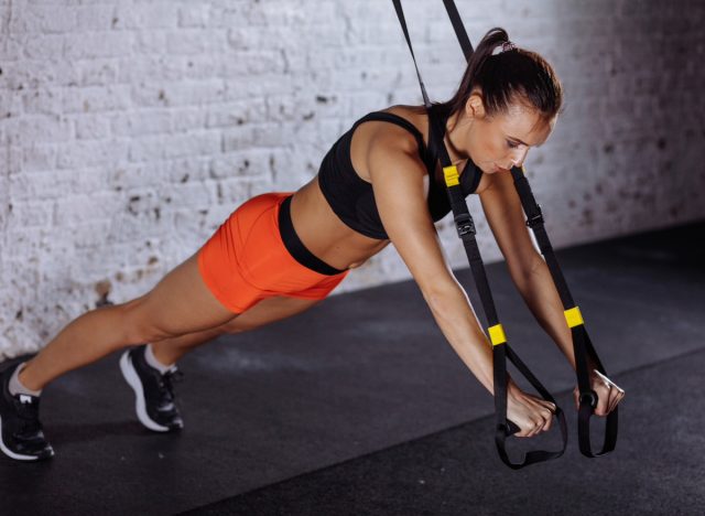 woman doing TRX pushups, concept of strength workouts for weight loss
