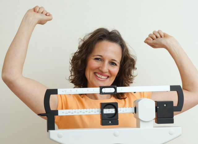 happy woman on scale, weight loss, concept of ways to reduce inflammation to make weight loss easier