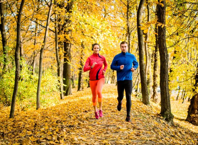 couple autumn jog on trail with foliage, concept of exercises to boost immunity
