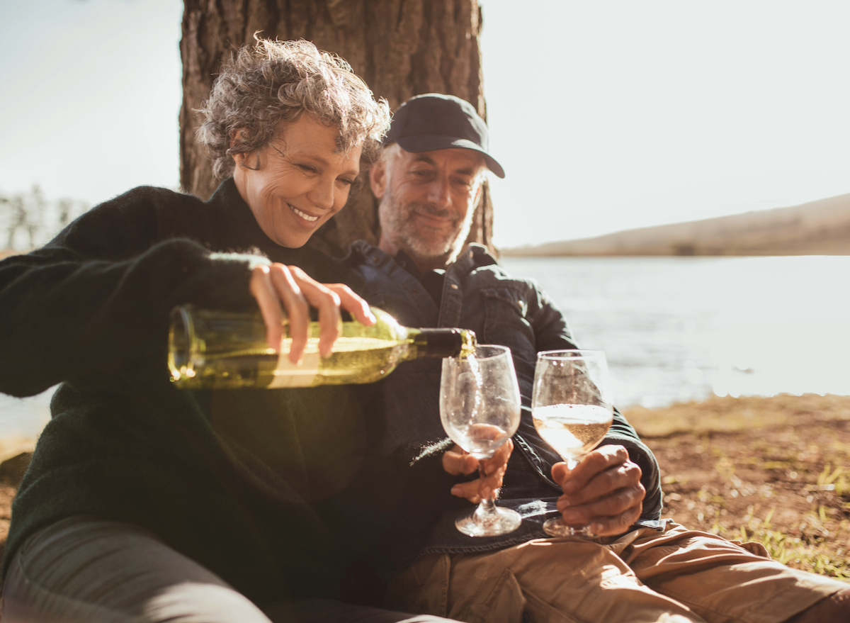mature couple enjoying wine by lake, concept of Mediterranean lifestyle tips to live longer