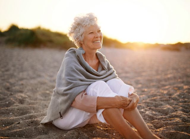 mature woman happy sitting at the beach, concept of brain exercises to stay mentally sharp