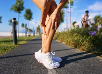 runner dealing with muscle cramping, concept of reasons why you cramp while working out