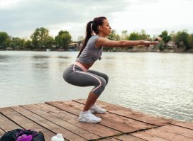 woman squatting next to lake, concept of standing workouts for women to lose weight