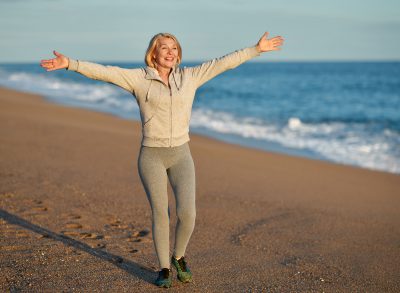 woman happy walking on the beach, concept of exercises for women to live longer