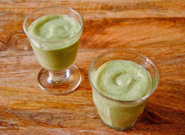two glasses of green smoothie on a wooden table