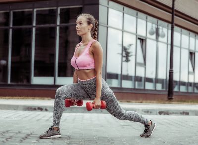 woman doing dumbbell lunges, concept of morning exercises for all-day energy