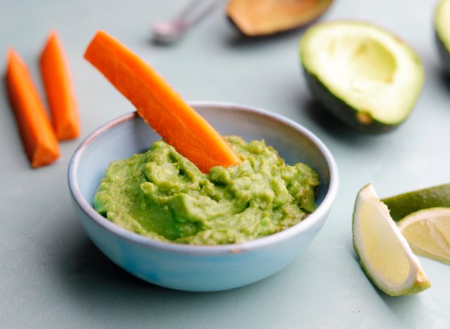 dipping carrots vegetables into guacamole