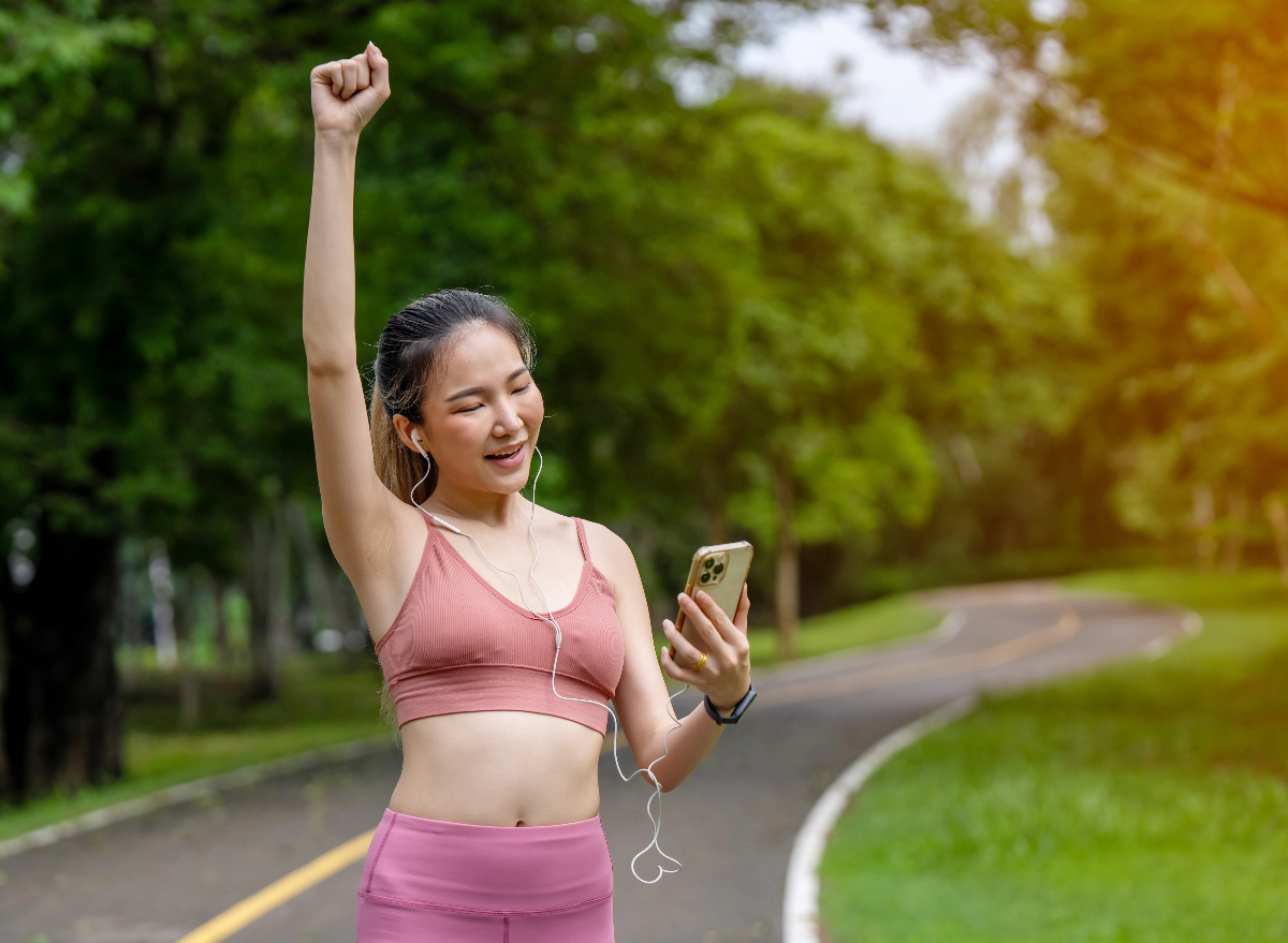 happy woman looking at phone on walk, concept of WeWard app helps you get paid to walk