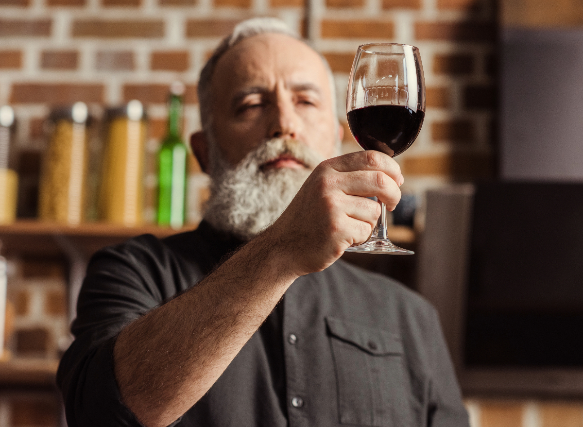 mature man holding red wine glass, concept of worst habits for bones