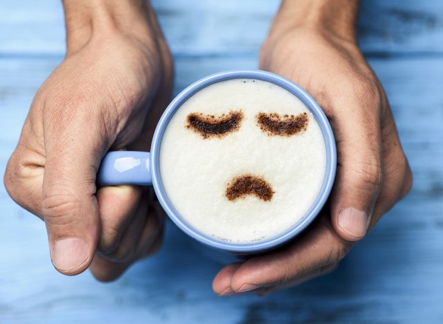 latte with a sad face drawn with cocoa powder on the milk foam