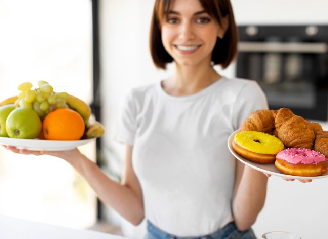 woman holding a plate of fruit and desserts