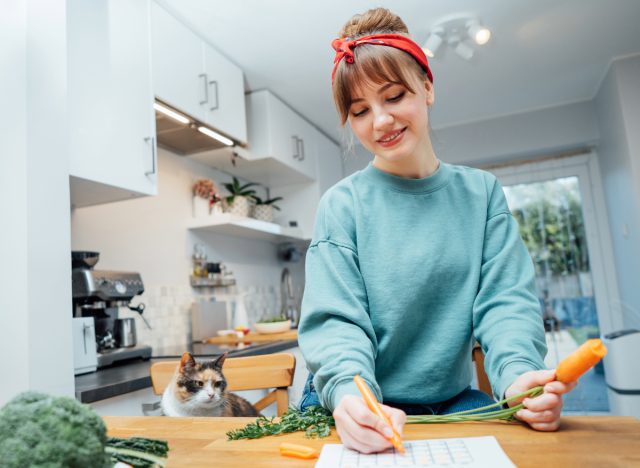 woman writes meal prep schedule on calendar