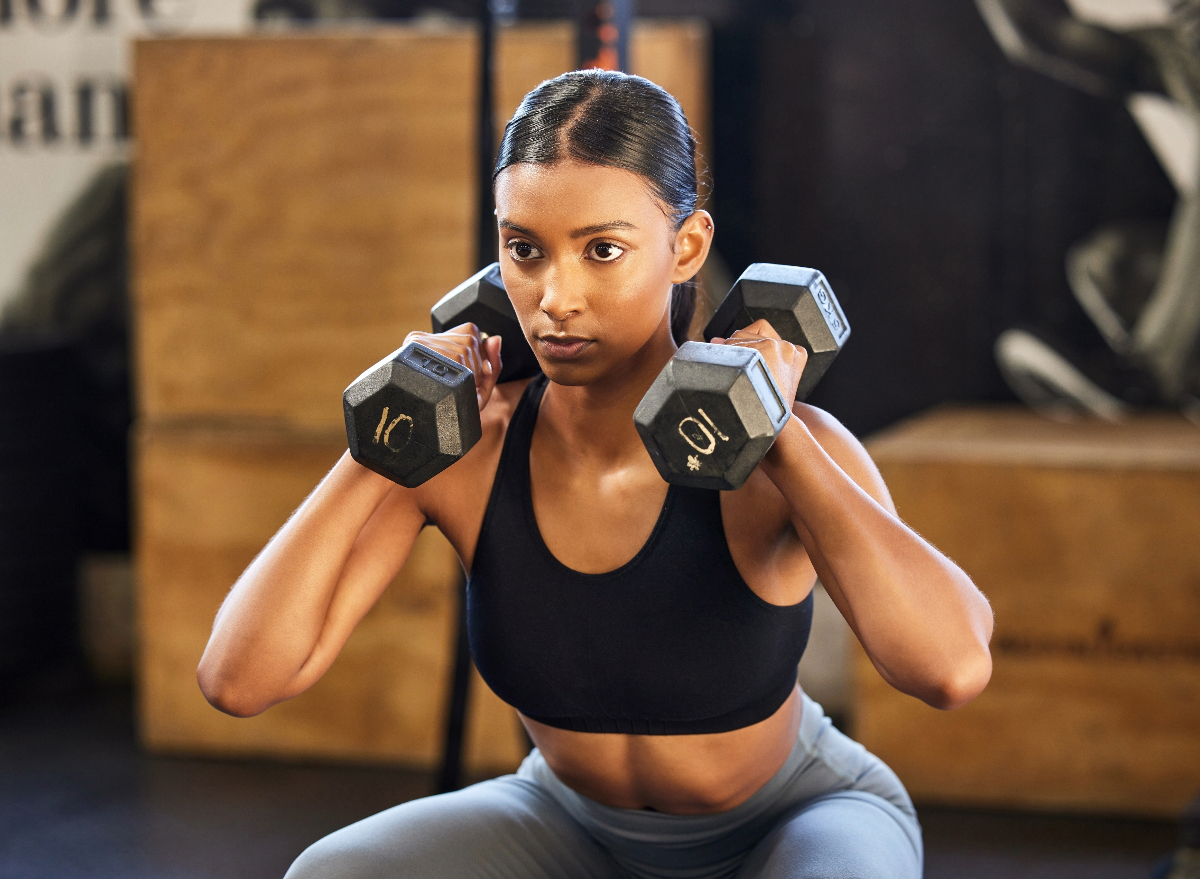 woman doing dumbbell squat to press, concept of exercises to melt lower belly fat
