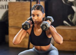 woman doing dumbbell squat to press, concept of exercises to melt lower belly fat