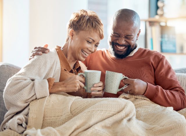 happy couple cuddling on the couch in the morning with coffee