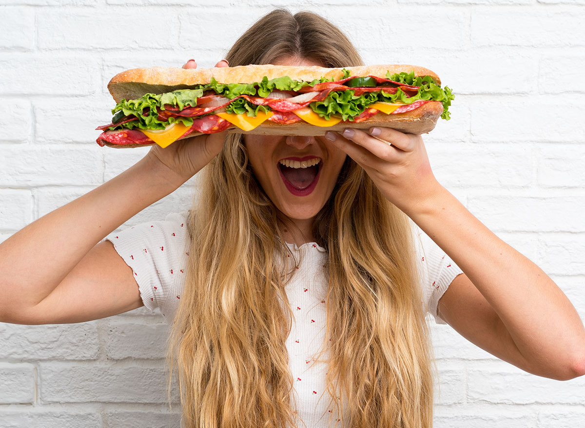 Happy,Young,Blonde,Woman,Holding,A,Big,Sandwich