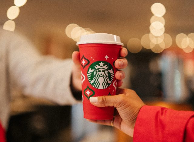 starbucks employee giving customer reusable red cup