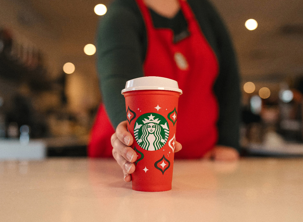 starbucks employee holding reusable red cup
