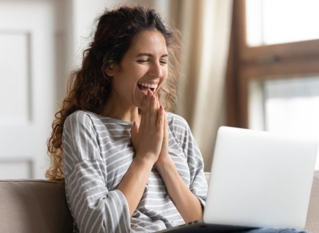 happy woman looking at laptop laughing