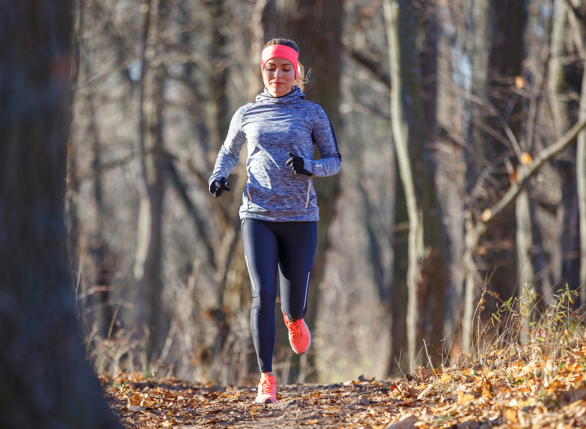 woman running through woodsy trail in the fall, concept of why you're not losing weight with cardio