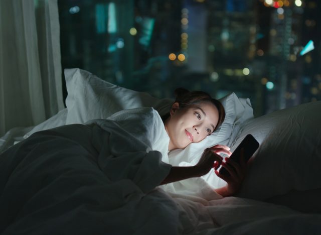 woman scrolling through social media in bed