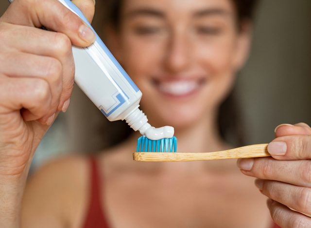 woman putting toothpaste on toothbrush
