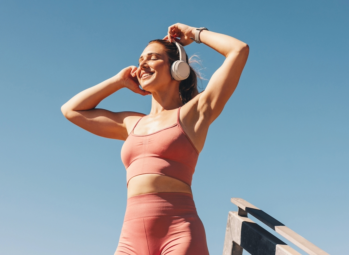 happy woman exercising outdoors, listening to music, concept of inspirational quotes to get moving