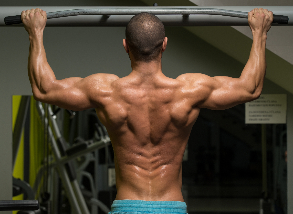 muscular man doing pull-ups concept of exercises to boost muscle growth