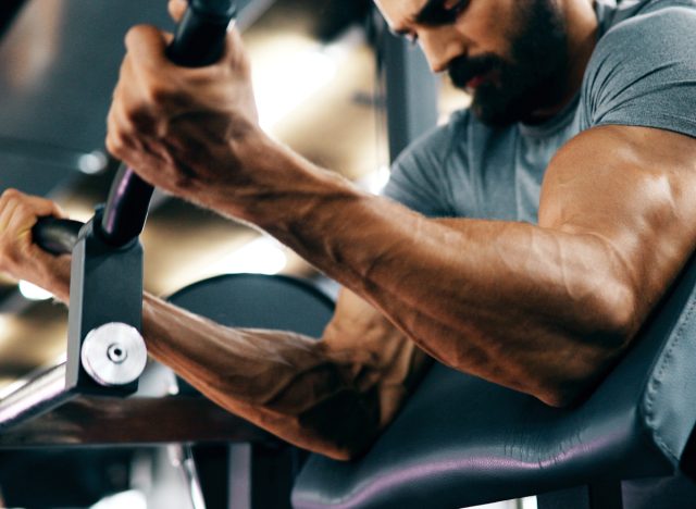 muscular man working out at workout machine, concept of exercise habits that completely destroy your body