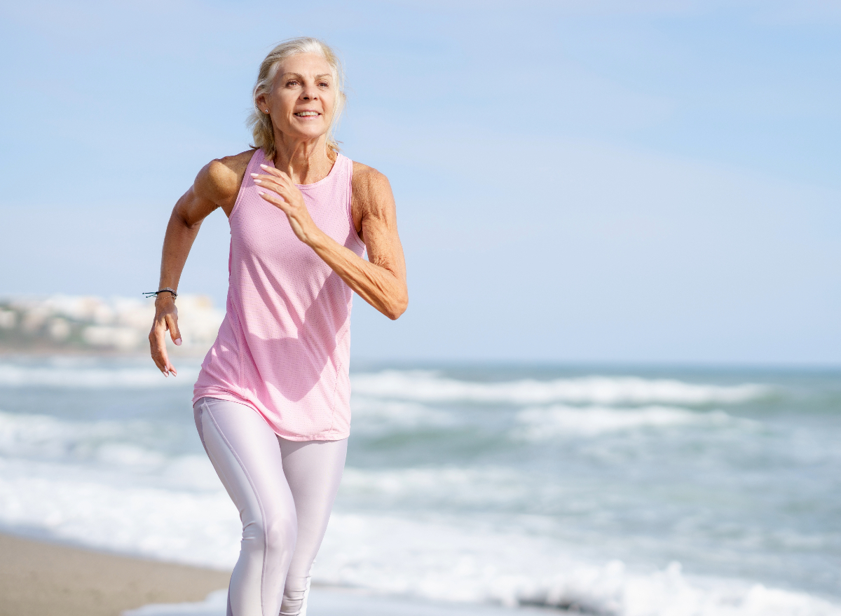 mature woman running on beach, concept of how often to work out for weight loss