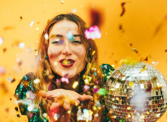 New Year's concept, woman holding disco ball with confetti