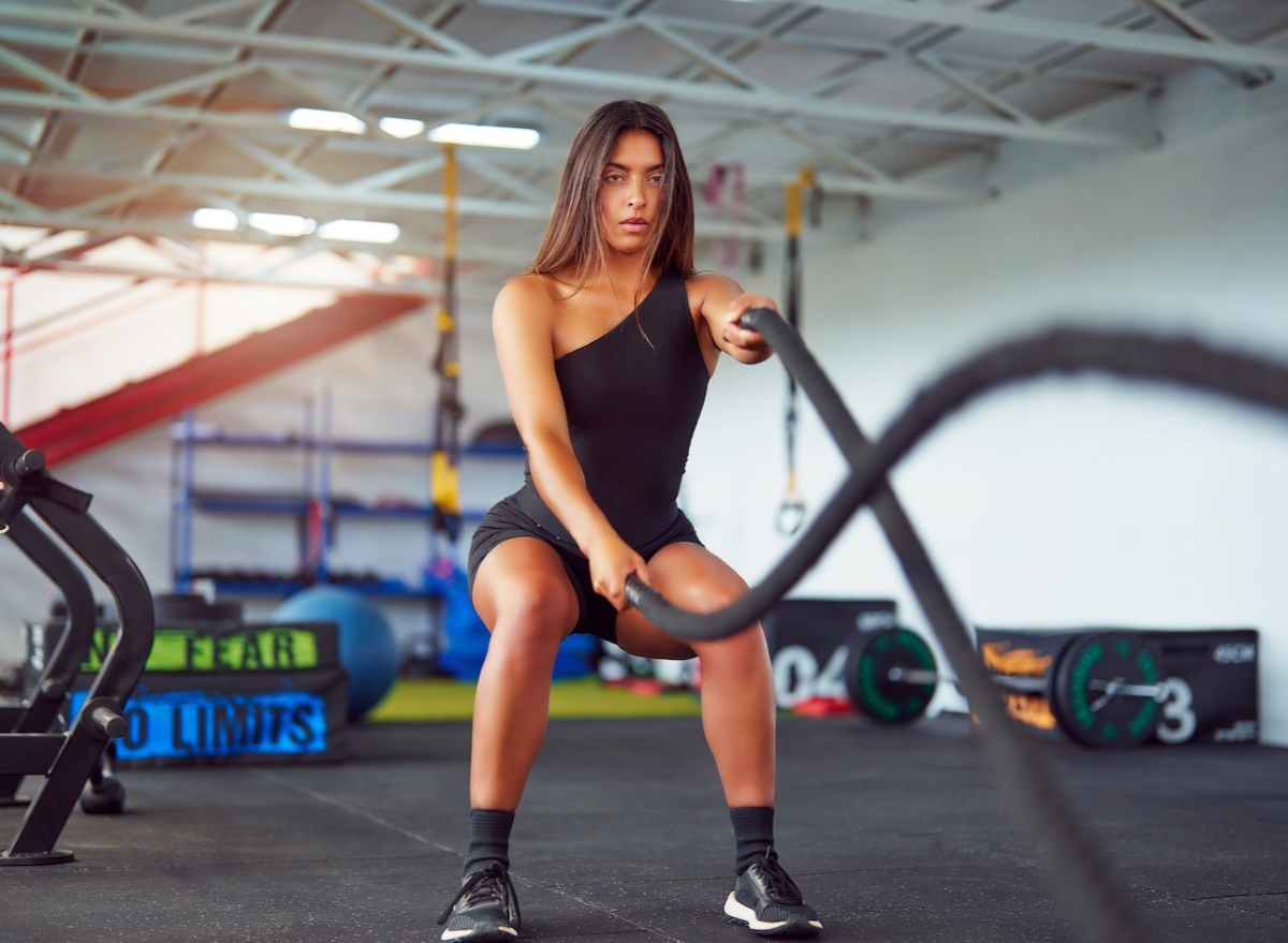 fit woman doing battle ropes exercise, concept of HIIT exercises for weight loss