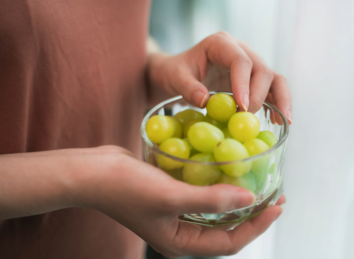 woman holding grapes, concept of can eating grapes help you lose weight