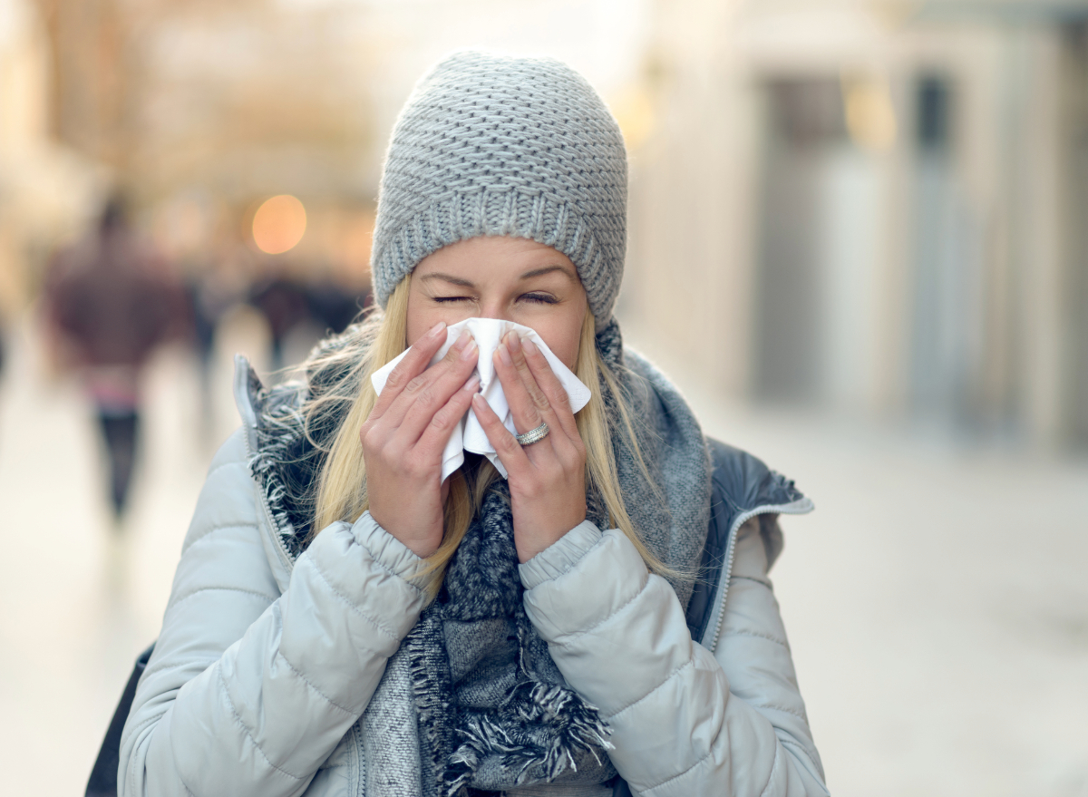 woman sneezing outdoors, concept of places most likely to get the flu