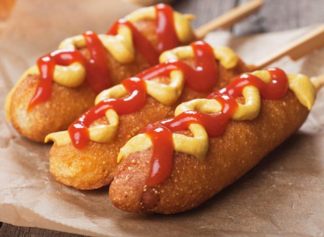 three corn dogs with ketchup and mustard