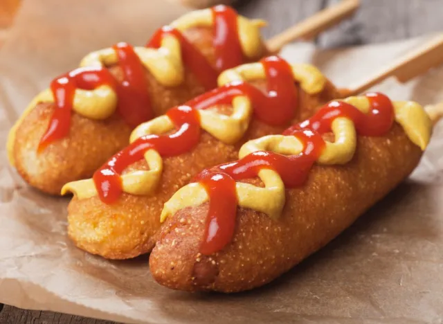 three corn dogs with ketchup and mustard