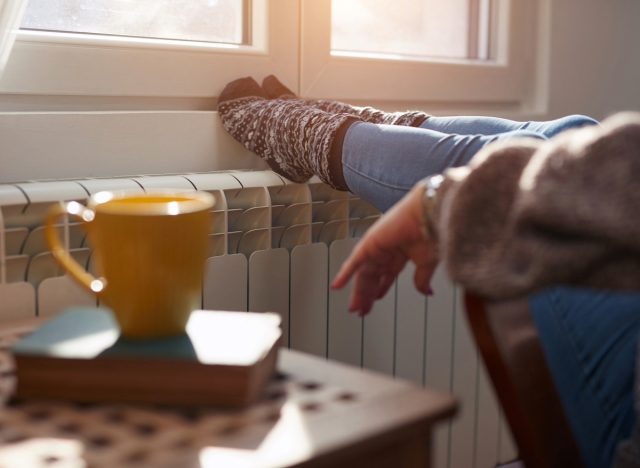 woman relaxing next to indoor heater on winter's day