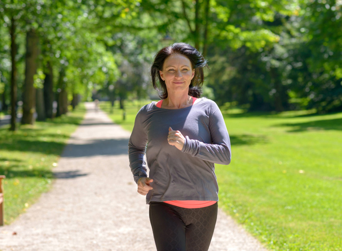 middle-aged woman running outdoors, concept of how often to do cardio to lose belly fat