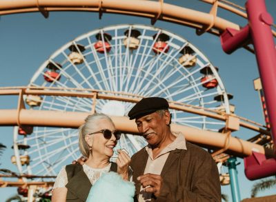 older couple enjoying cotton candy at carnival or theme park, concept of the places you're most likely to catch COVID