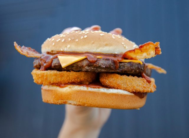 person holding carl's Jr. western bacon cheeseburger