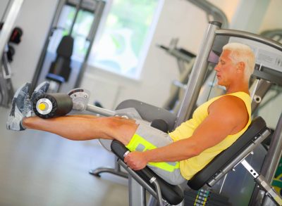 senior man doing leg exercise at the gym, concept of leg-strengthening workout for seniors
