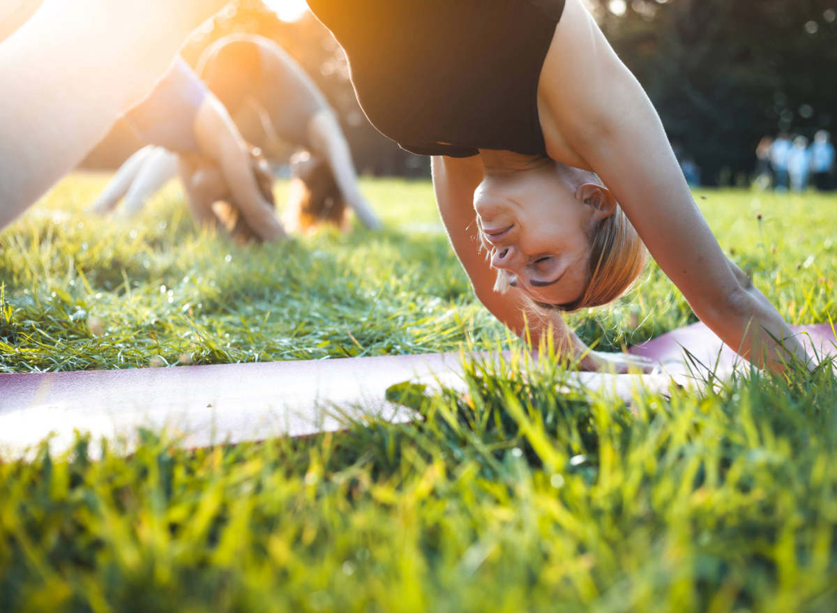 woman doing downward dog in park, concept of workouts to regain balance