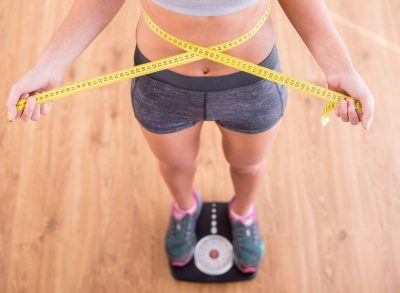 fitness woman measuring waist on scale, concept of at-home workouts to get lean