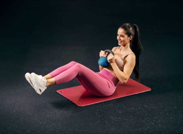 woman doing kettlebell twist, concept of strength workouts for apron belly